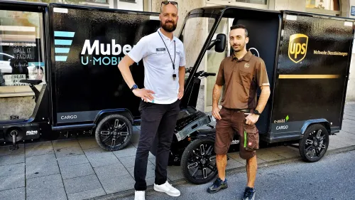 Two young persons standing in front of eCargo Bikes, one of them branded with UPS.
