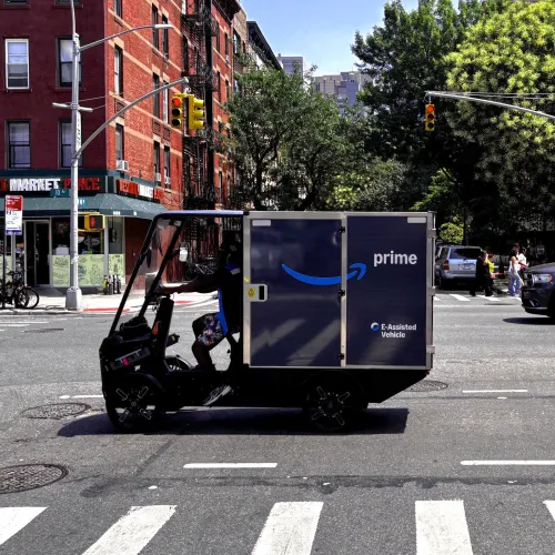 eCargo Bike branded with Amazon driving trough NYC in front of green trees